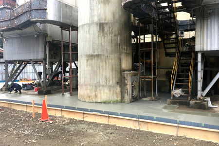 施設周辺に仮設の土間のコンクリートを打設しています。煙突の基部が見えます。