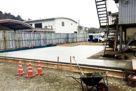 施設周辺に仮設の土間のコンクリートを打設しています。仮囲いが見えます。