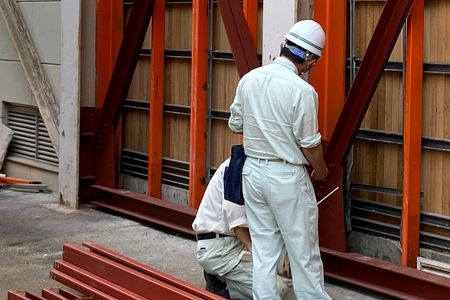 当財団職員が外壁の耐震補強の確認をしています。外側から鉄骨のフレームを追加しています。