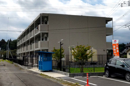 定住促進住宅の外観です。南東からベランダのある南面を見ています。色はベージュ基調です。