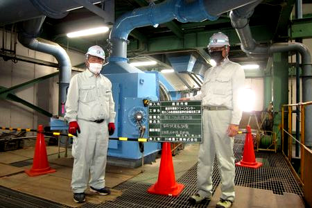 当財団職員が粗大ごみ処理施設を確認しています。ダクトがつながった青い機械が見えます。