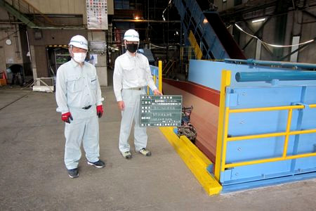 当財団職員が粗大ごみ処理施設を確認しています。ベルトコンベアーがつながった青い機械が見えます。