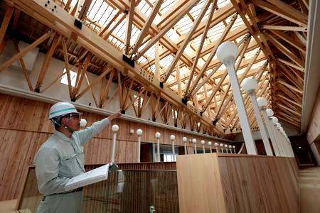 当財団職員が建物内部を確認しています。吹き抜けを覆う木造のトラスが見えます。